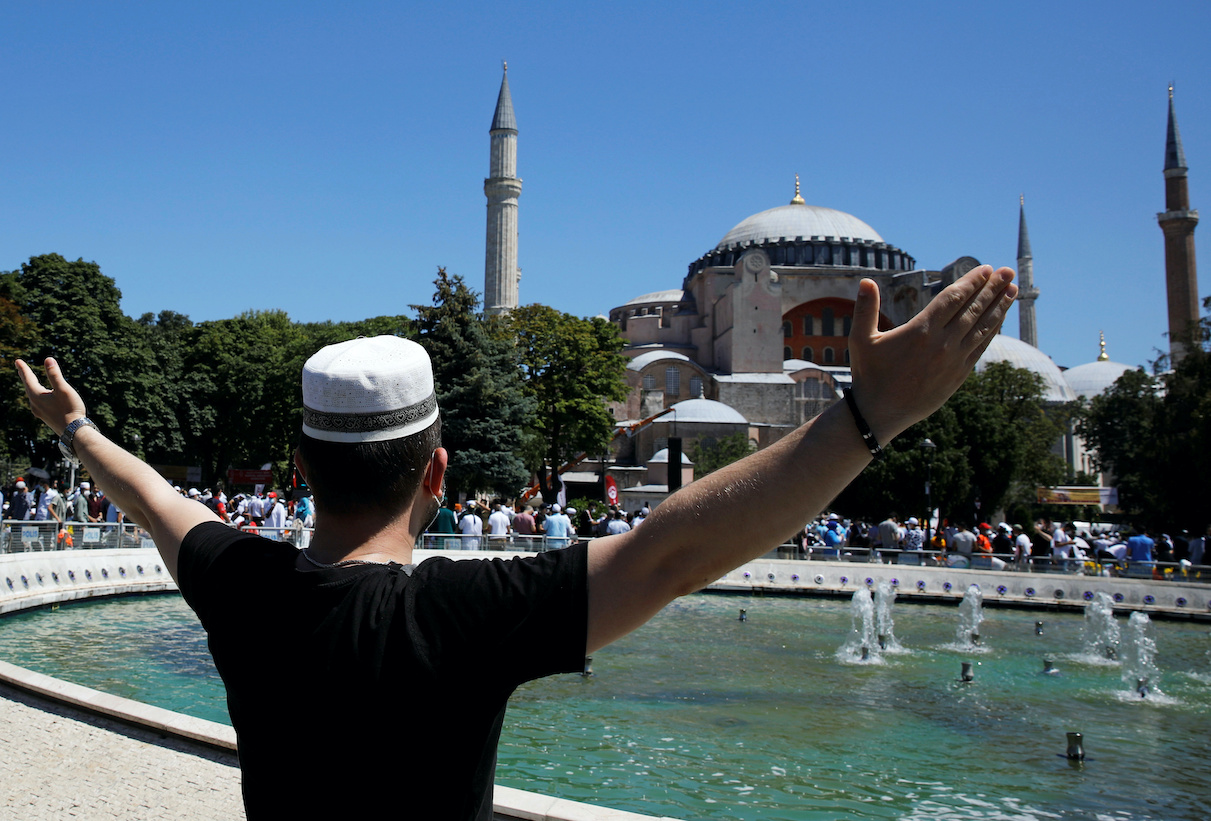 A man gestures as people wait for the beginning of Friday prayers outside Hagia Sophia Grand Mosque, for the first time after it was once again declared a mosque after 86 years, in Istanbul, Turkey, July 24, 2020. REUTERS/Umit Bektas
