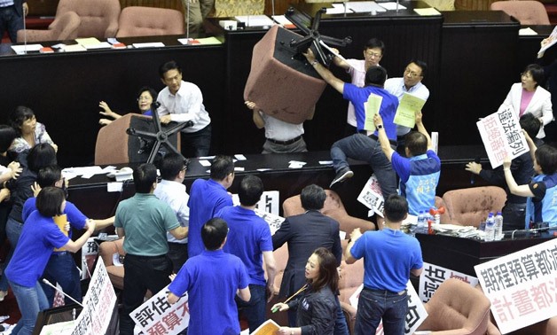 Opposition lawmakers raised large padded office chairs above their heads, surrounding the podium and tussling with rival legislators  - AFP/SAM YEH