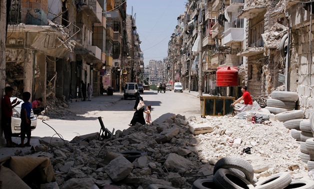 A woman walks with a child amid rubble at Bustan al-Qasr neighbourhood in Aleppo, Syria July 16, 2017. REUTERS/Omar Sanadiki
