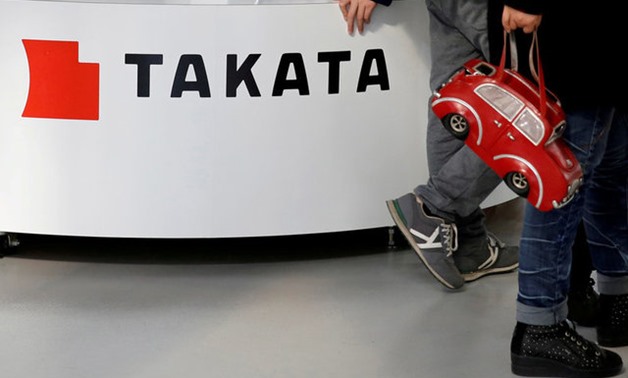 Visitors walk past a logo of Takata Corp on its display at a showroom for vehicles in Tokyo - Reuteers