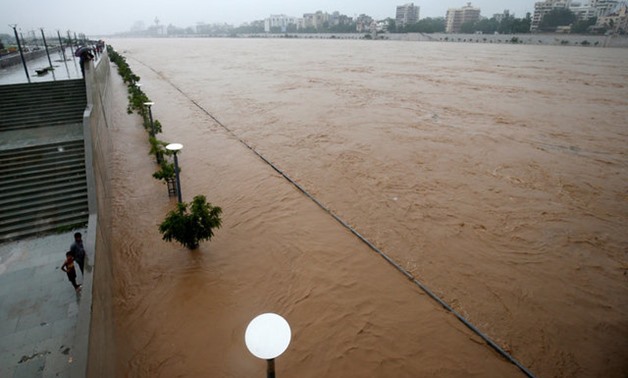 People stand on the promenade along the flooded Sabarmati river after heavy rain in Ahmedabad, India, July 25, 2017. REUTERS/Amit Dave

