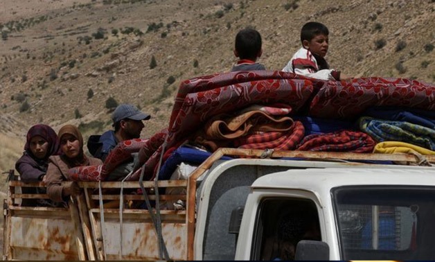 Syrian Refugees seen on the back of a truck at Lebanon's border region of Arsal - Reuters