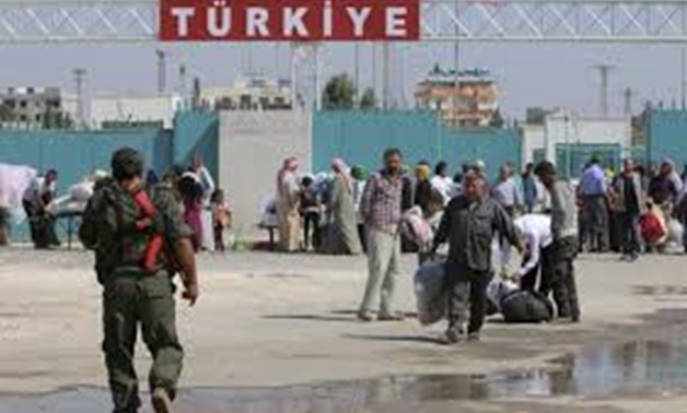 A Kurdish People's Protection Units (YPG) fighter walks near residents who had fled Tel Abyad as they re-enter Syria from Turkey, after the YPG took control of the area in Tel Abyad town, Raqqa governorate, Syria, June 23, 2015.
