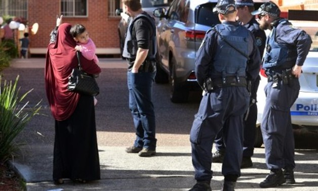 © AFP | Police direct locals around a block of flats in the Sydney suburb of Lakemba after counter-terrorism raids across the city
