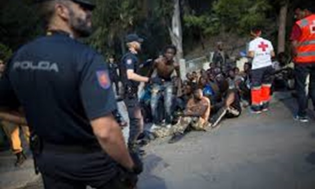 Police stand around a group of African migrants as Red Cross workers attend the injured after they crossed the border fence from Morocco to Spain's North African enclave of Ceuta, Spain August 1, 2017.
