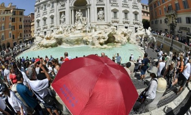 © AFP / by Angus MACKINNON | Sightseers shelter from the sun under an umbrella in front of Trevi fountain in Rome as temperatures reached more than 40 degrees Celsius.
