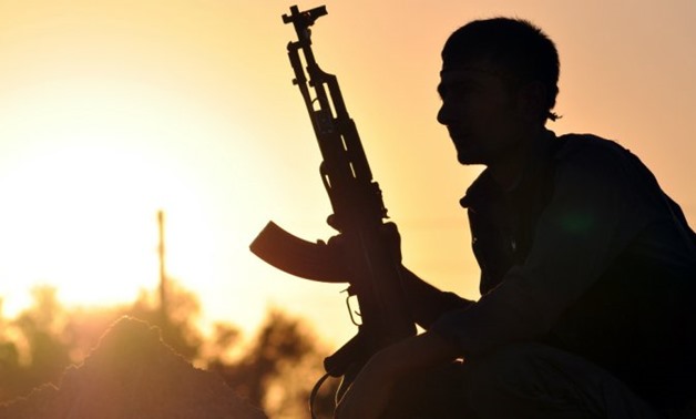 © DELIL SOULEIMAN / AFP | A fighter from the Kurdish People's Protection Unit (YPG) poses for a photo at sunset in the Syrian town of Ain Issi, some 50 kilometres north of Raqqa.
