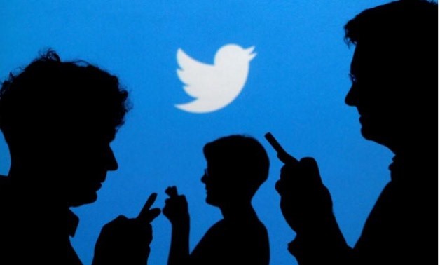 People holding mobile phones are silhouetted against a backdrop projected with the Twitter logo in this illustration picture taken - Reuters
