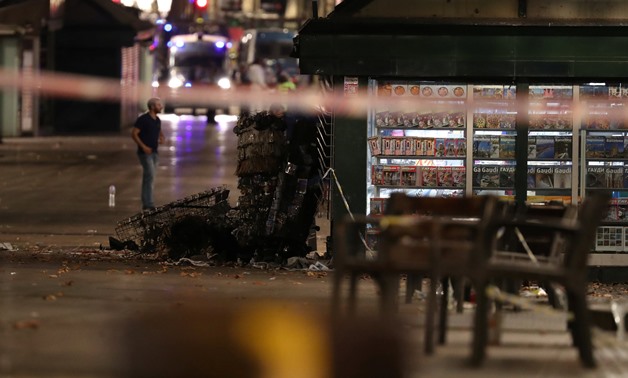 A officer walks past a fallen post cards display near the area where a van crashed into pedestrians at Las Ramblas in Barcelona, Spain, August 18, 2017. REUTERS/Sergio Perez