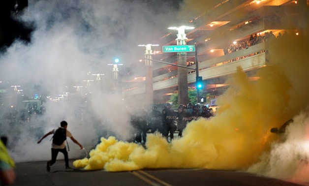 Police officials lob tear gas to try and disperse demonstrators after a Donald Trump campaign rally in Phoenix - REUTERS