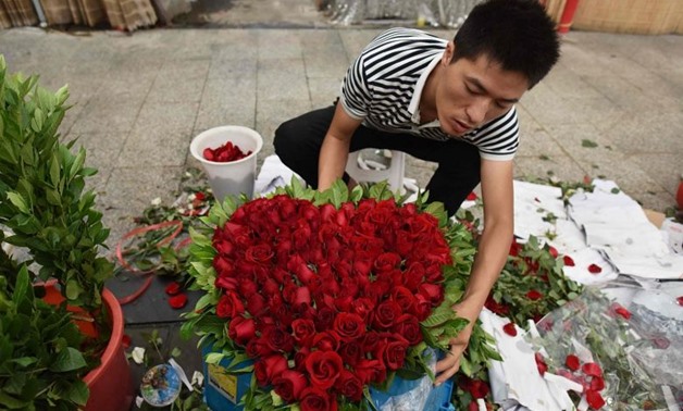 A florist preparing a heart-shaped bouquet of roses at a flower market in Beijing on Aug 25, 2017. PHOTO: AFP