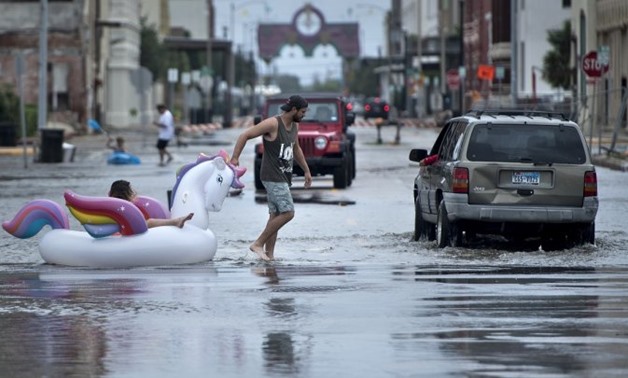 © Brendan Smialowski / AFP | People make their way down partially flooded roads following the passage of Hurricane Harvey on August 26, 2017 in Galveston, Texas