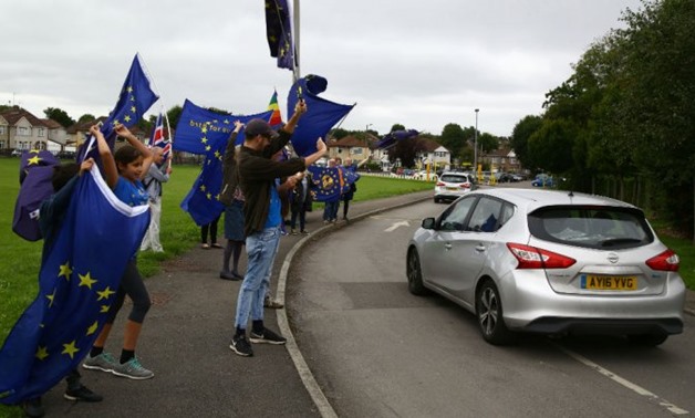 © Geoff Caddick / | Britain's opposition Labour party leader Jeremy Corbyn drives past supporters holding EU flags outside a members' meeting, as part of his summer campaign tour, in Bristol on August 11, 2017.