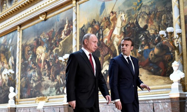 Emmanuel Macron (R) speaks to Vladimir Putin (L) in the Galerie des Batailles (Gallery of Battles) as they arrive for a joint press conference at the Chateau de Versailles before the opening of an exhibition marking 300 years of diplomatic ties between th