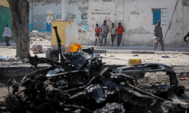 Young Somalis look on near the wreckage of a car bomb after a double suicide attack by Al Shabaab at a popular Mogadishu restaurant – FILE/AMISOM Public Information