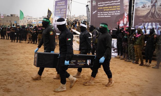 Hamas' Al Qassam Brigades hand over a coffin containing the body believed to be that of Shiri Bibas, a mother captured by the brigades along with her husband and two children on October 7, 2023. - Hamas