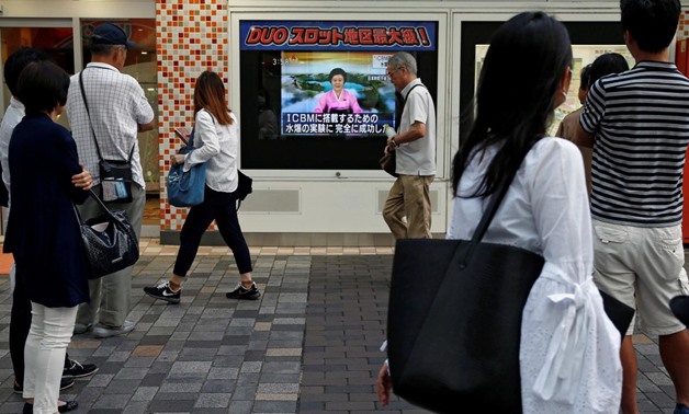 People walk past a street monitor showing a news report about North Korea's nuclear test, in Tokyo, Japan, September 3, 2017. 