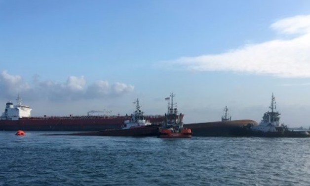 © Maritime and Port Authority of Singapore/AFP | This handout photograph taken by Singapore's Maritime and Port Authority shows tugboats moving the capsized dredger