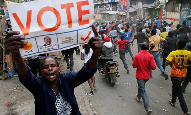 A supporter of Kenyan opposition leader Raila Odinga carries a banner and shouts slogans as others run along a street in Humura neighbourhood, in Nairobi, Kenya August 10, 2017. Photo: Reuters/Thomas Mukoya.