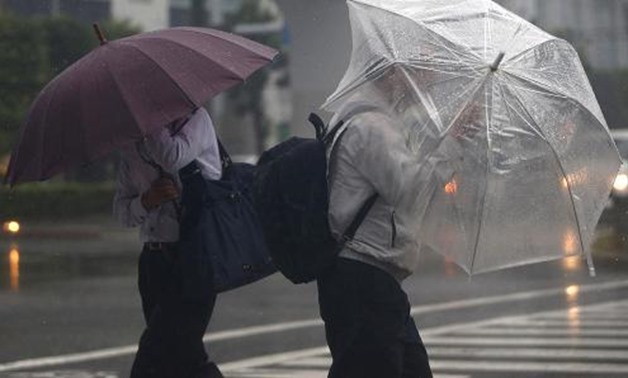 Passers-by with umbrellas struggle against strong winds and heavy rain caused by Typhoon Phanfone, in Tokyo October 6, 2014.