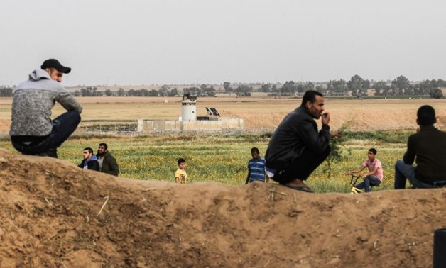 Palestinians sit near the Gaza-Israel border on the outskirts of Khan Yunis in the southern Gaza Strip on March 28, 2018 - AFP 
