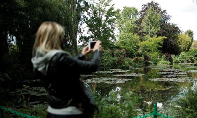 A woman takes pictures from the bridge at the nympheas pond garden as she visits the reopened Claude Monet house and foundation after restrictions to prevent the spread of the coronavirus disease (COVID-19) were eased, in Giverny - REUTERS/Benoit Tessier