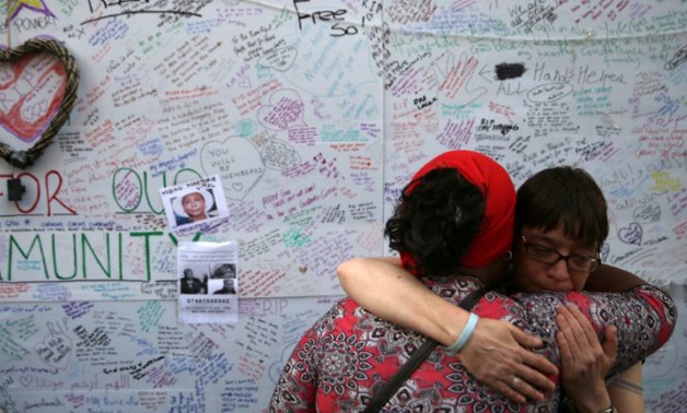 Two women embrace in front of a messages left on a wall of condolence following the blaze at Grenfell Tower (AFP Photo/Daniel LEAL-OLIVAS