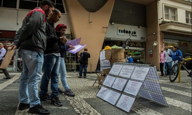 Unemployed Brazilians read job announcements in downtown Sao Paulo - AFP 